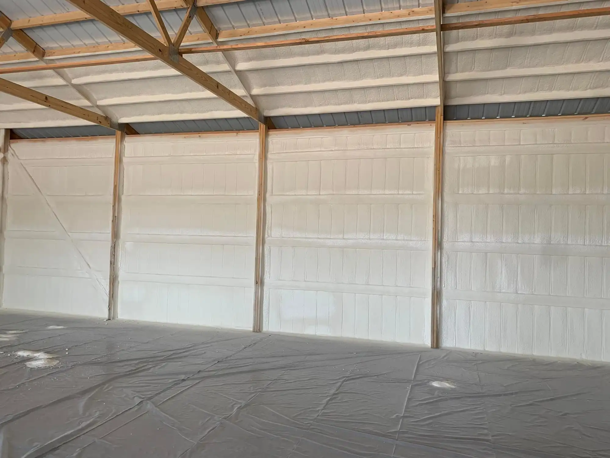 Installer applying spray foam insulation inside a building